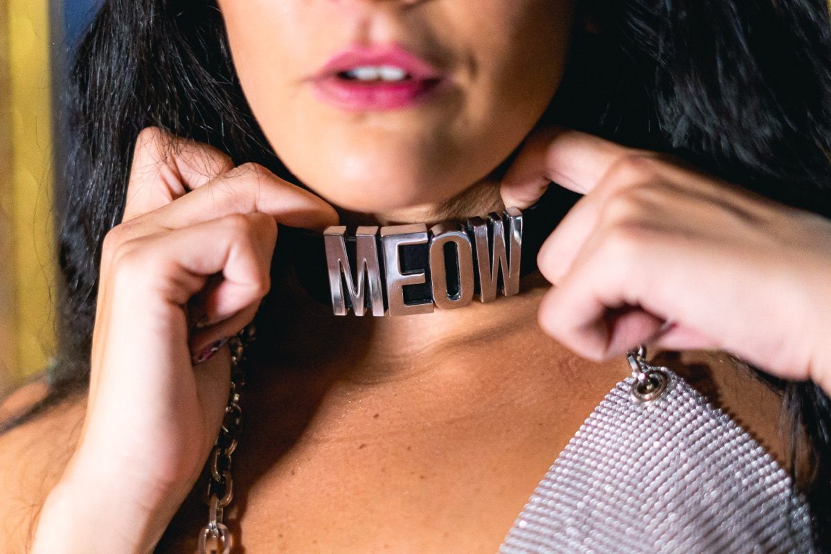 Close de um choker de metal com as letras MEOW no pescoço de uma convidada