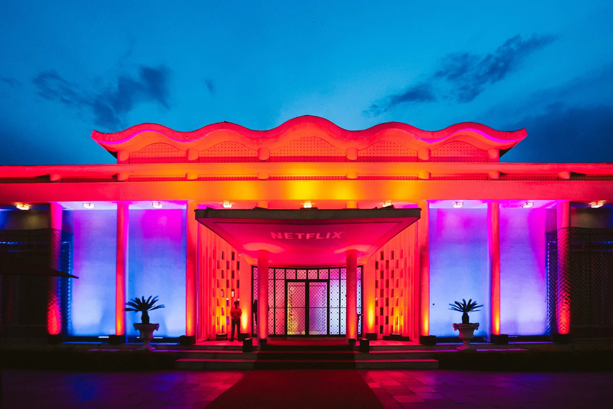 A fachada modernista da Casa Panamericana lavada de vermelho e roxo na noite da festa