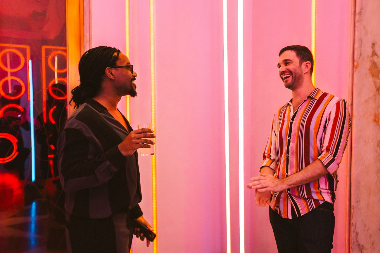 Convidados conversando sob luz de neon