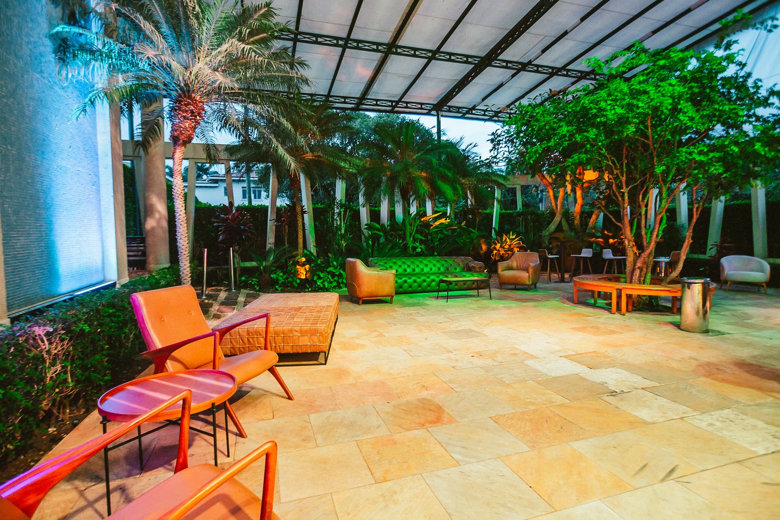 Jardim de inverno da casa iluminado, com poltronas e palmeiras