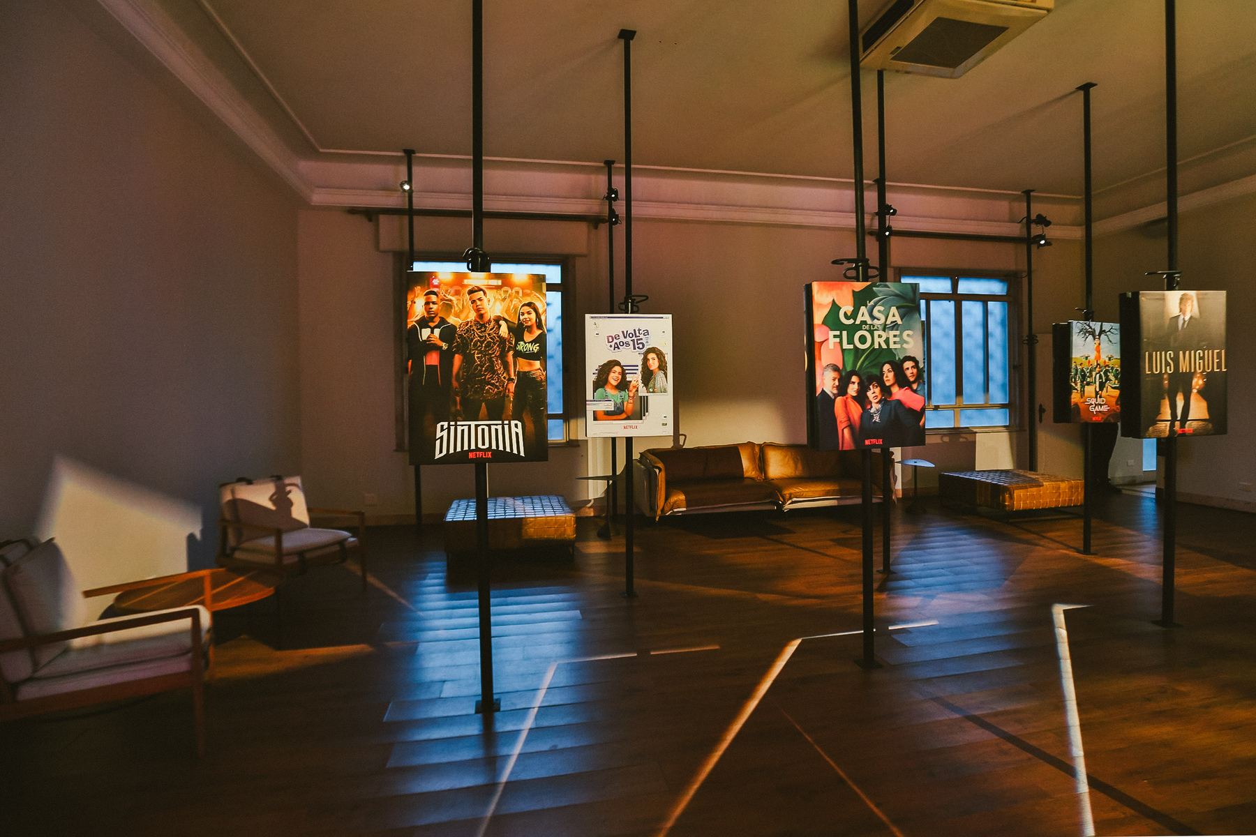 Salão com os pôsteres dos títulos do ano pendurados como numa galeria, com poltronas no meio