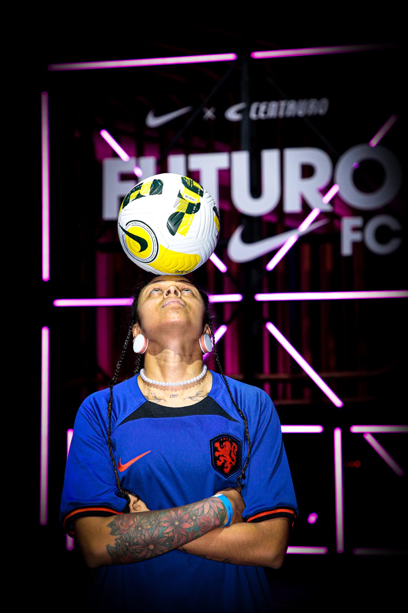 Freestyler equilibrando a bola na cabeça diante do painel Futuro FC
