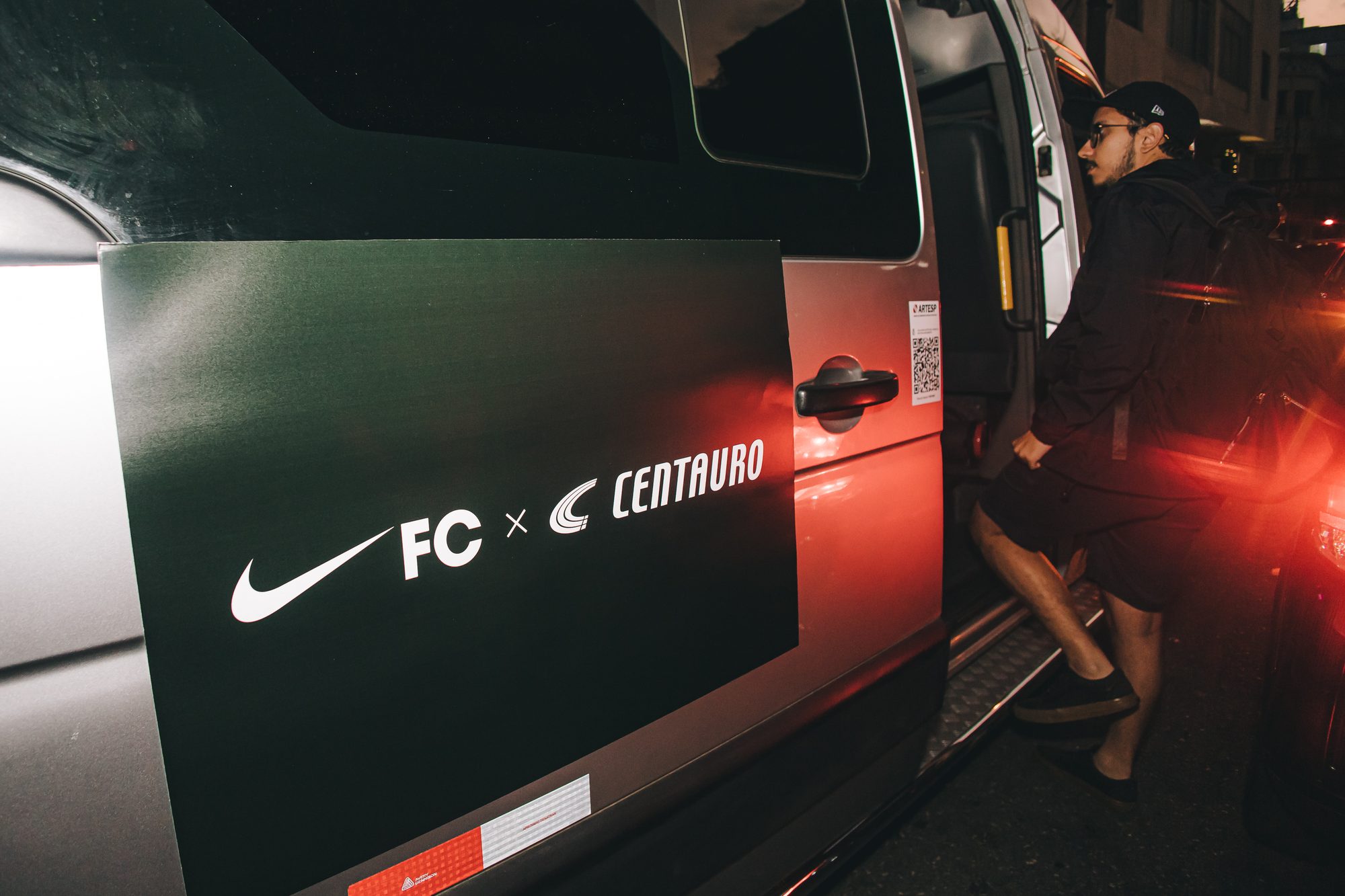 Van adesivada com Nike FC e Centauro parada na porta da loja, à noite