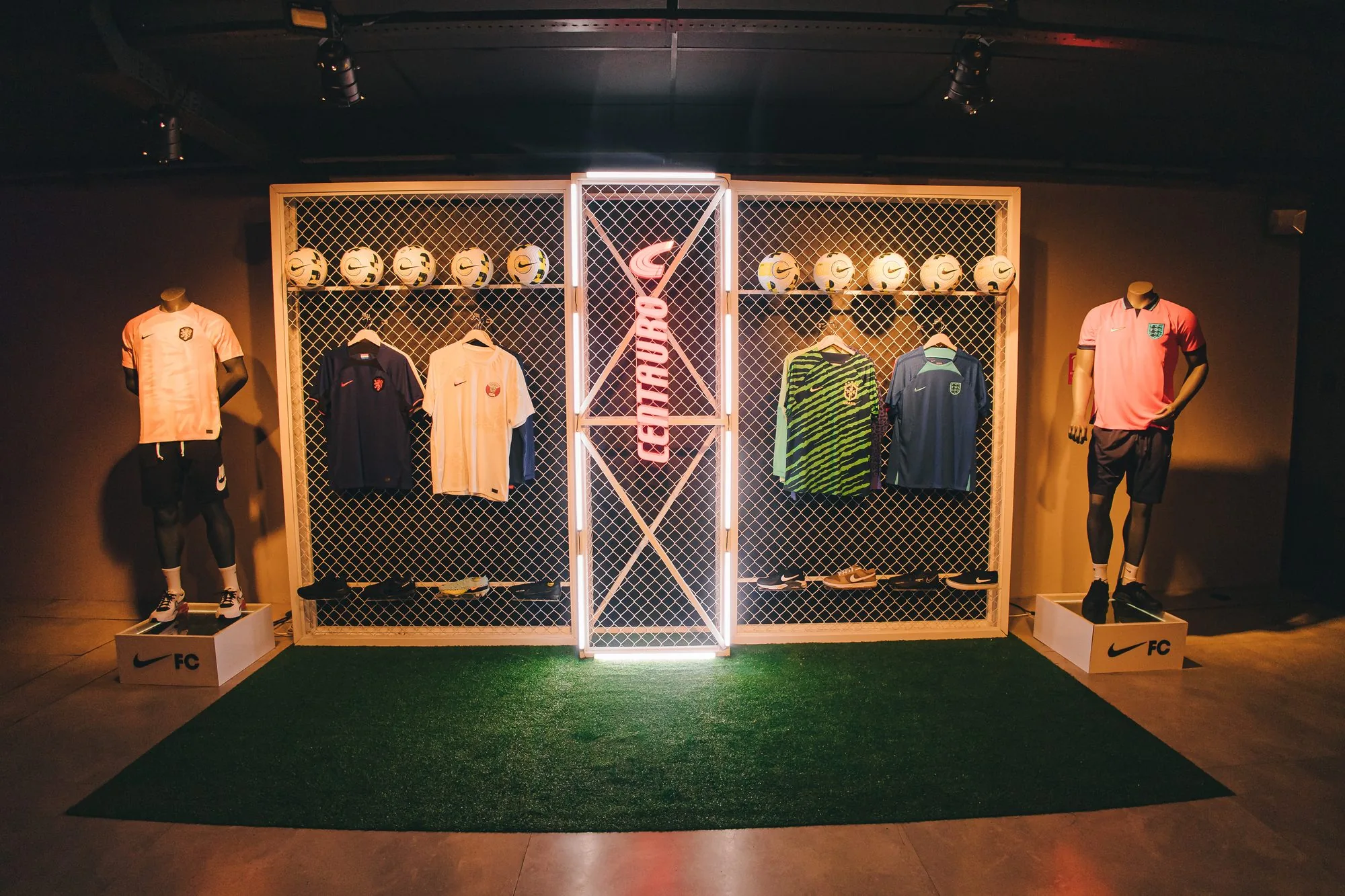 Vitrine iluminada com as camisas da coleção Garra Brasileira sobre grama sintética