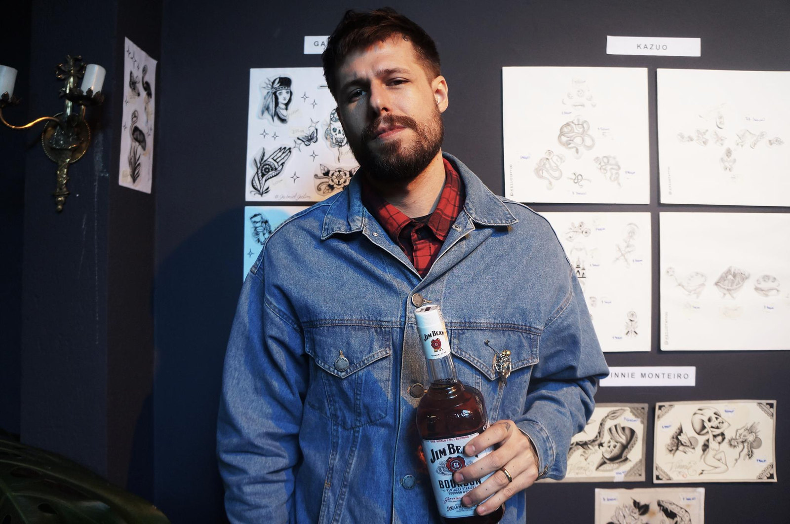 Convidado com garrafa de Jim Beam na frente da parede de flash art