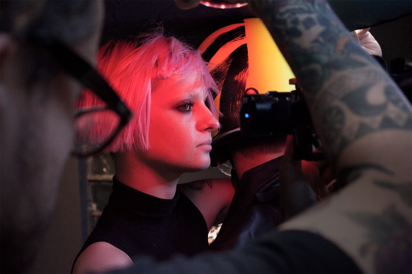 Fotógrafo enquadrando a modelo sob a luz vermelha do set