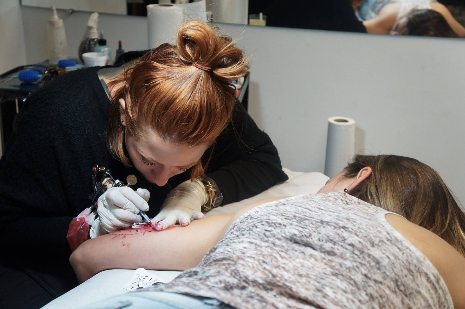 Tatuadora trabalhando no braço de uma cliente durante o evento